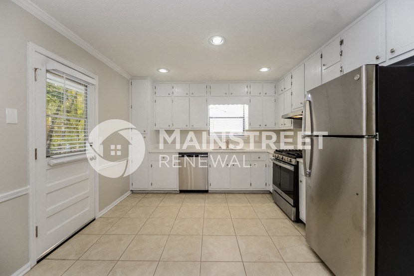 a renovated kitchen with white cabinets and a stainless steel refrigerator