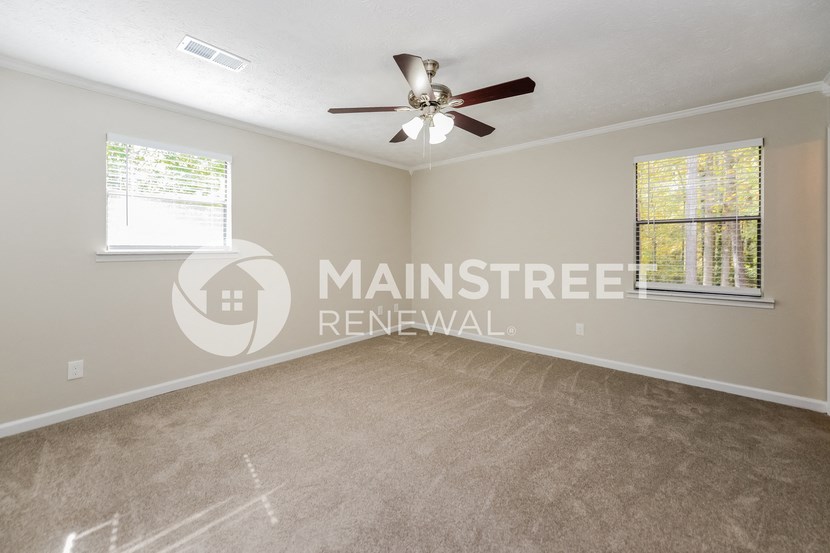 an empty living room with a ceiling fan and a window