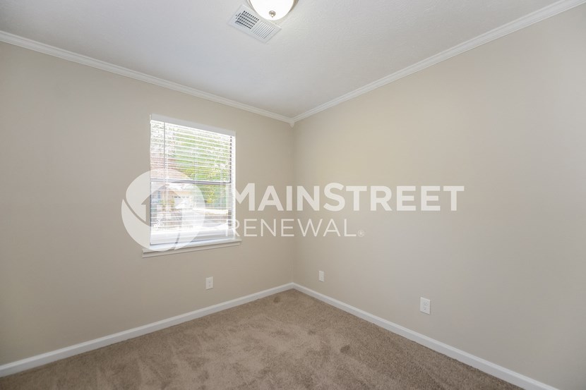 a bedroom with beige carpet and a window