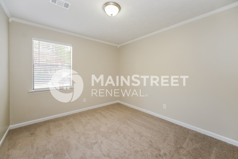 a bedroom with beige carpet and a window