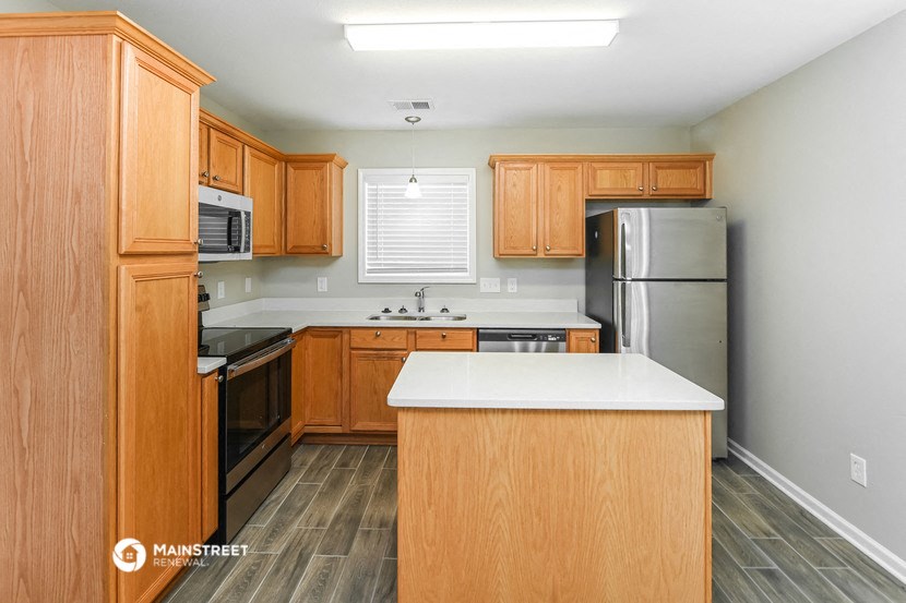 a kitchen with wooden cabinets and stainless steel appliances and a white counter top