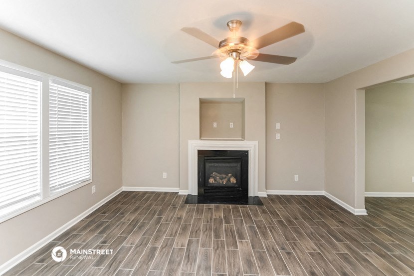 the living room has a fireplace and a ceiling fan