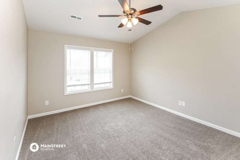 an empty room with a ceiling fan and a window