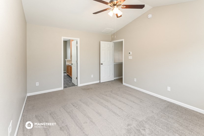 the spacious living room with carpet and a ceiling fan