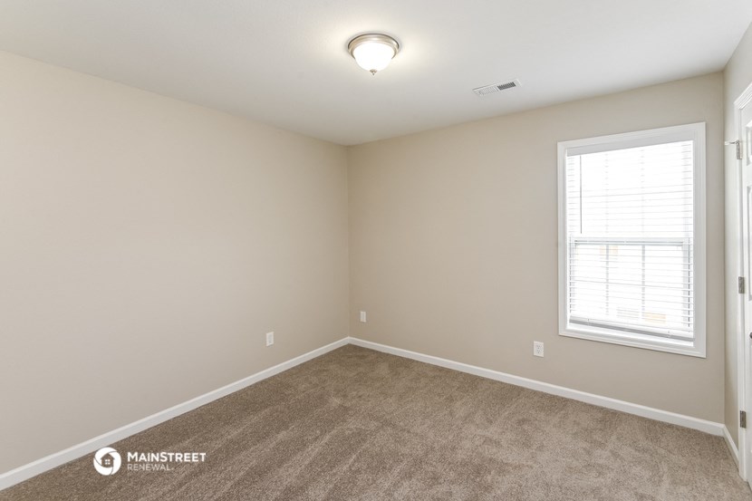 the spacious living room with carpeting and a window