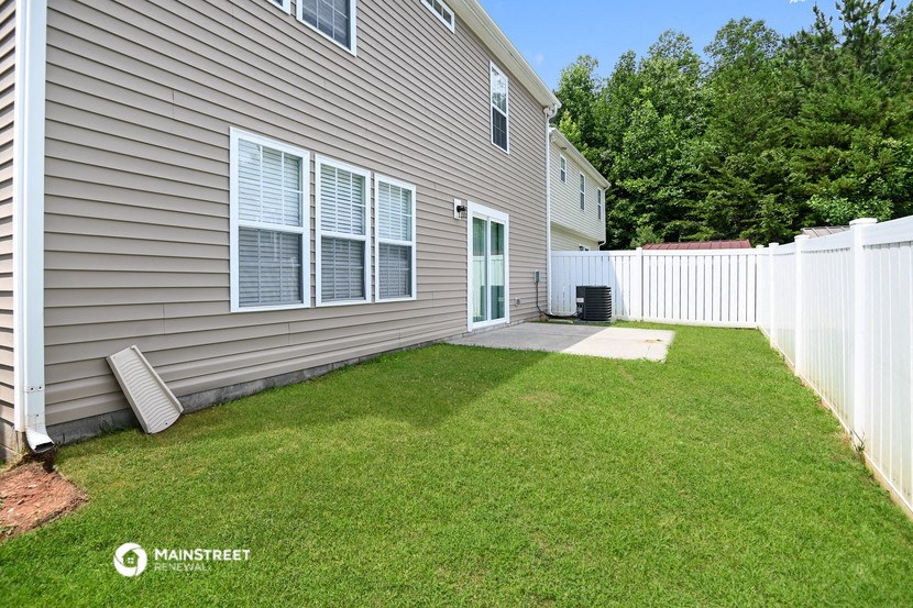 a side view of a house with a yard and a white fence