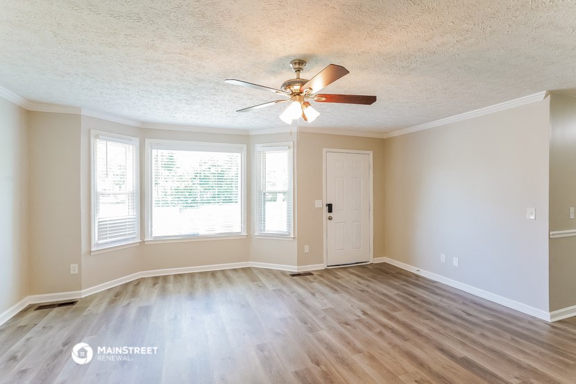 an empty living room with a ceiling fan and a window