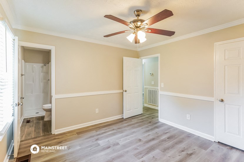 an empty living room with a ceiling fan and a bathroom