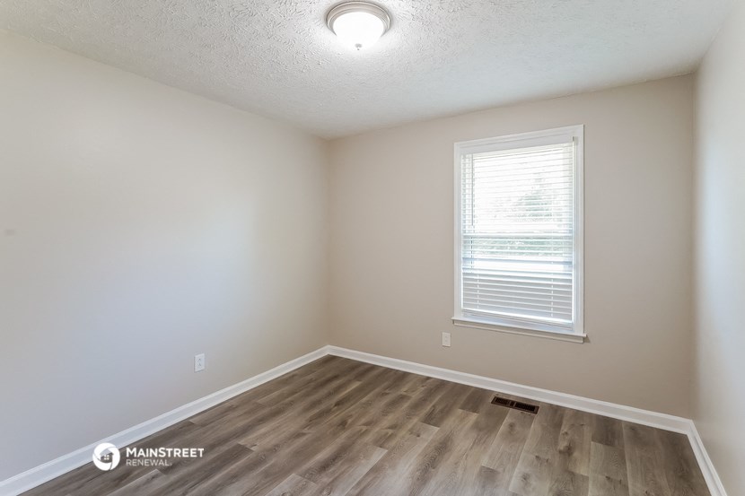 the spacious living room with hardwood flooring and a window