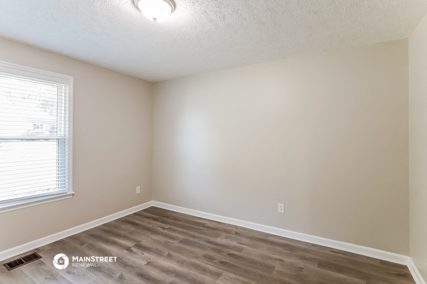 the interior of a bedroom with wood flooring and a window