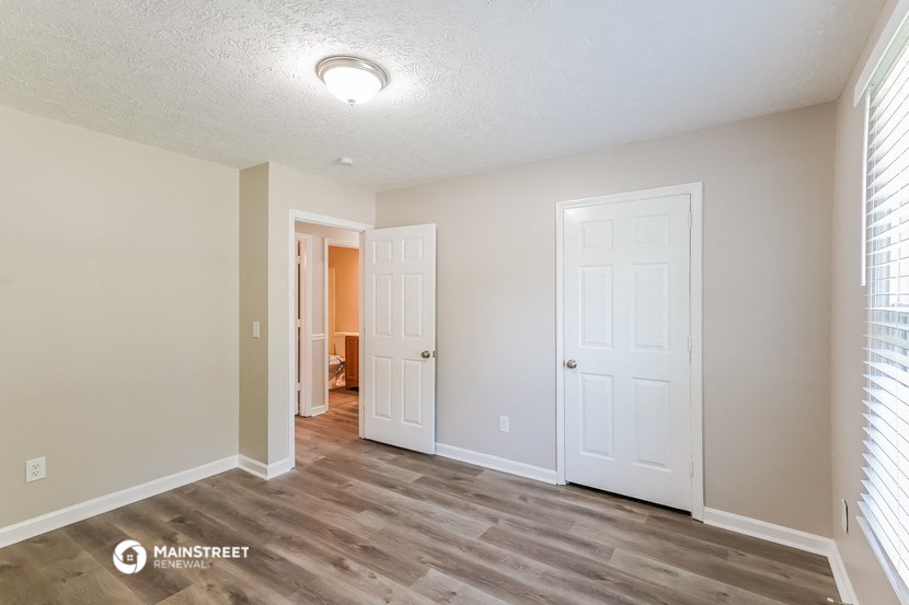 the spacious living room with white walls and wood flooring