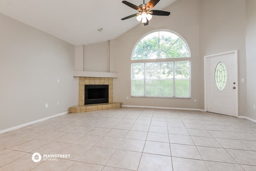 an empty living room with a fireplace and a ceiling fan