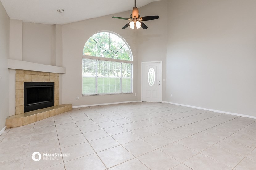 an empty living room with a fireplace and a ceiling fan