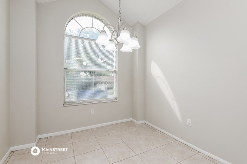 an empty dining room with a large window and a tiled floor