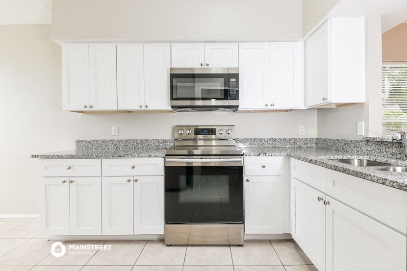 a kitchen with white cabinets and a stove and a microwave