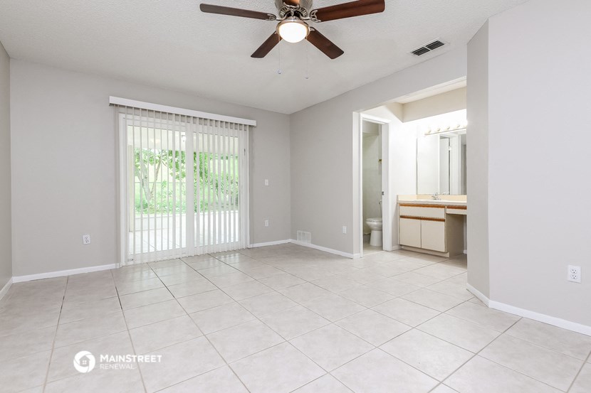 an empty living room with a ceiling fan and sliding glass doors