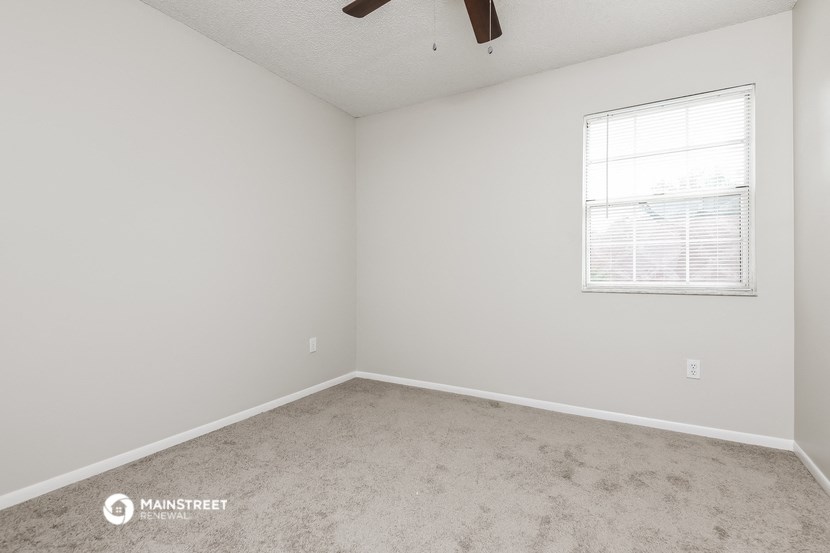 a bedroom with white walls and carpet and a window