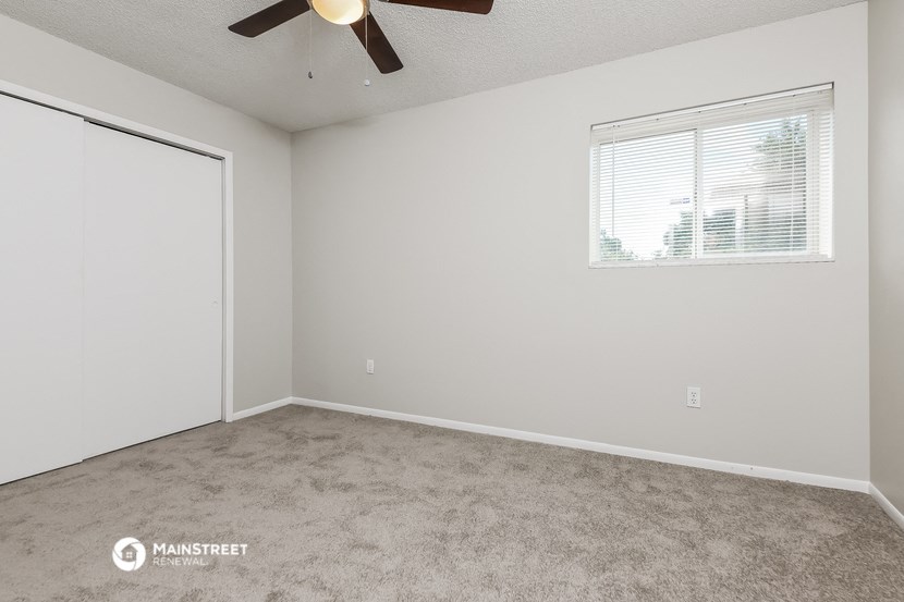 the spacious living room with carpet and a ceiling fan