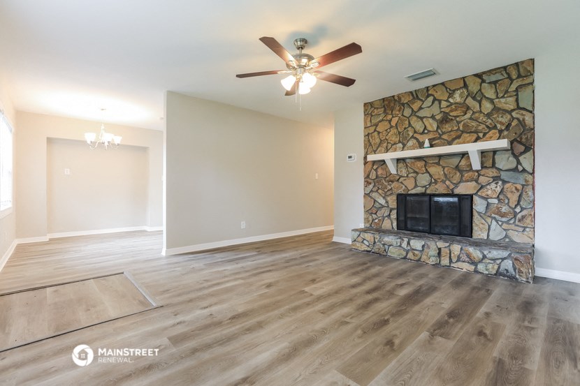 the living room has a stone fireplace and hardwood floors