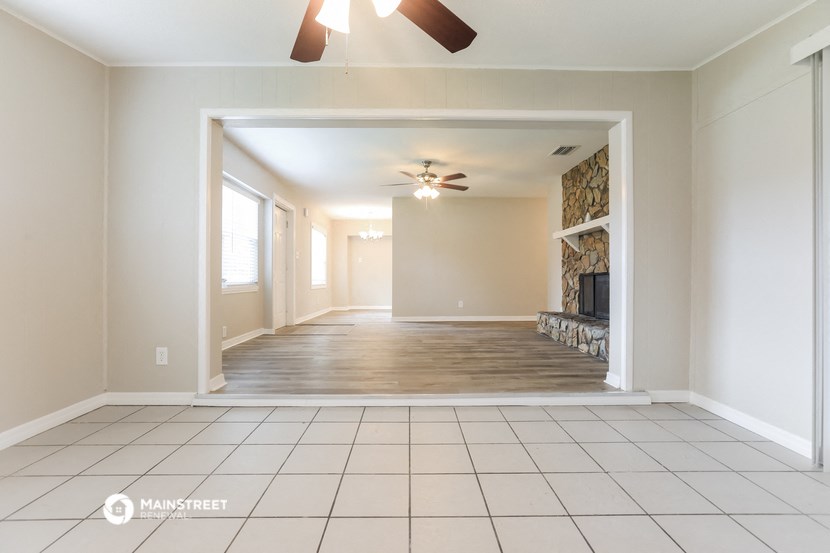 an empty living room with a fireplace and a ceiling fan