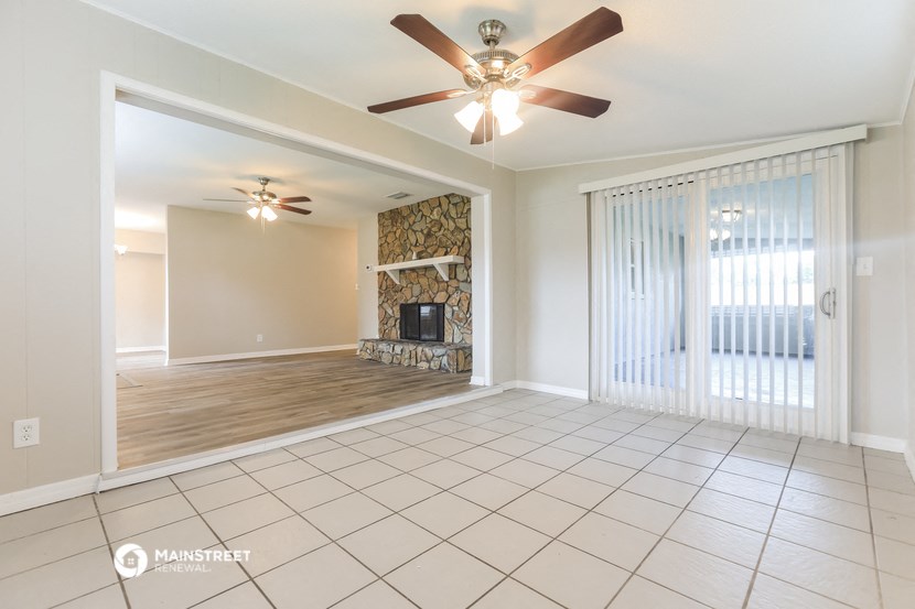 an empty living room with a fireplace and a ceiling fan