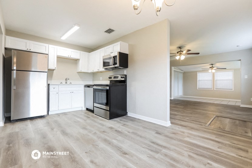 a kitchen and living room with white cabinets and stainless steel appliances