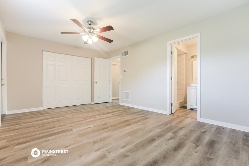 an empty living room with white walls and a ceiling fan
