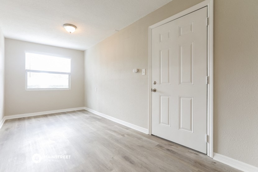 an empty room with a white door and a window