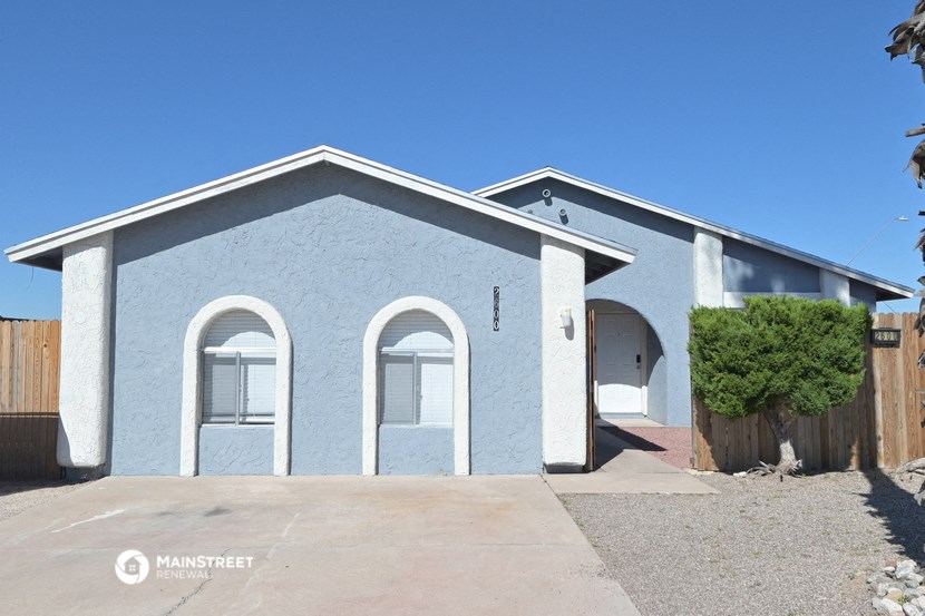 the front of a blue house with a driveway and a tree