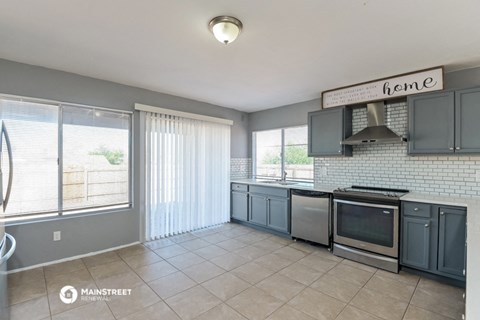 a kitchen with gray cabinets and stainless steel appliances