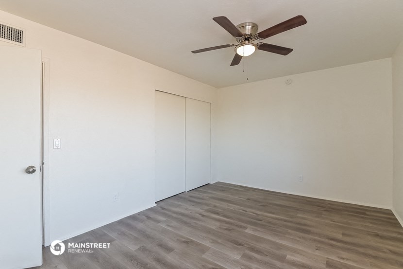 a bedroom with white walls and a ceiling fan