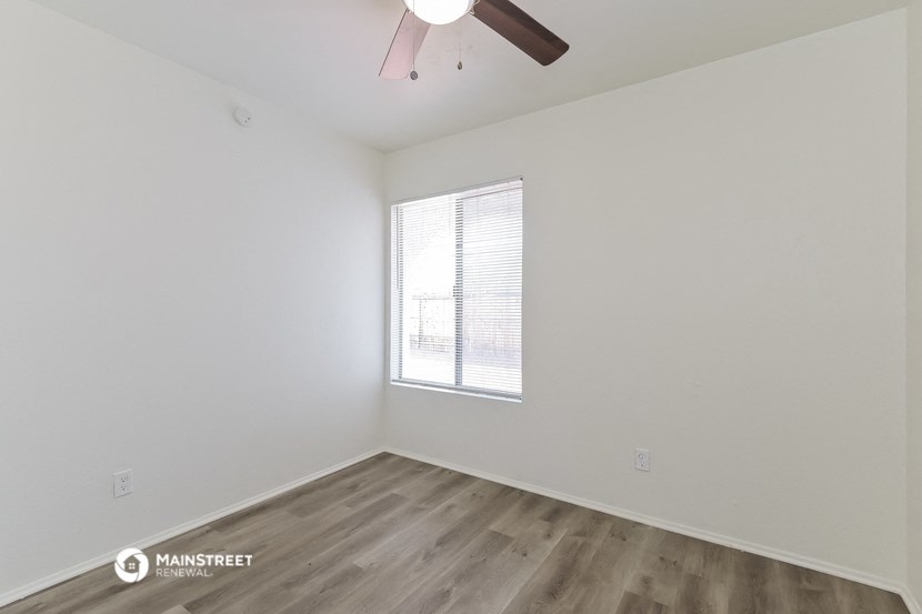 a bedroom with white walls and wood flooring and a window