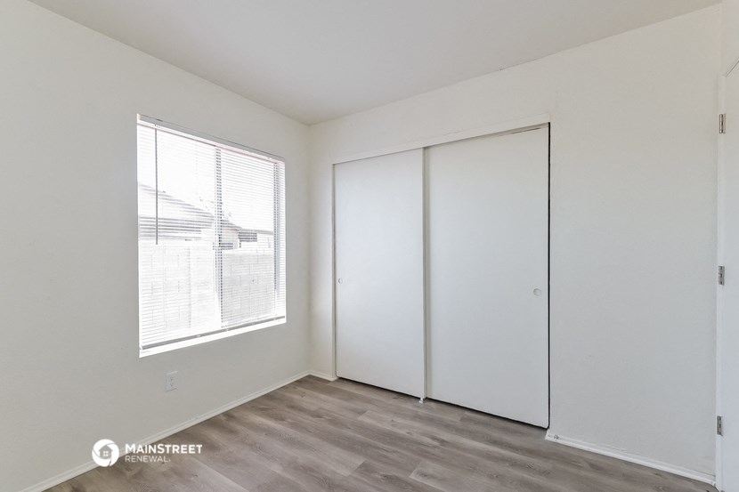 a bedroom with white walls and white closets and a window