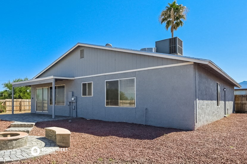 a gray house with a palm tree and a driveway