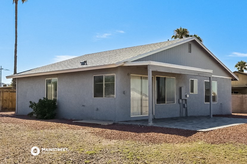 a small gray house with a yard and a palm tree