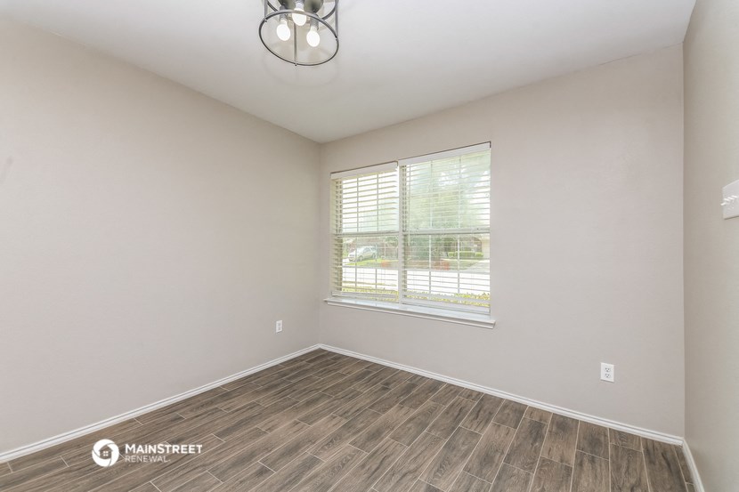 an empty living room with a large window and wood flooring
