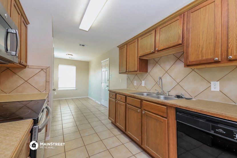 a kitchen with wooden cabinets and a black dishwasher and a sink