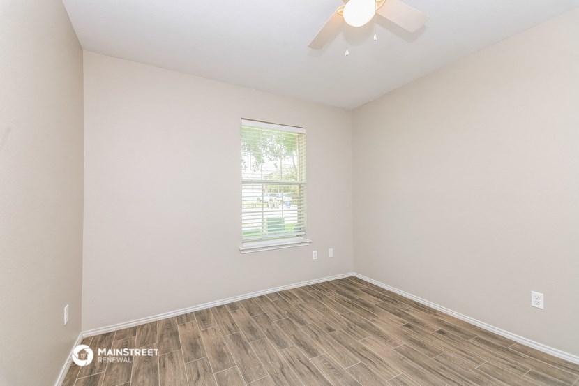 an empty room with a ceiling fan and a window