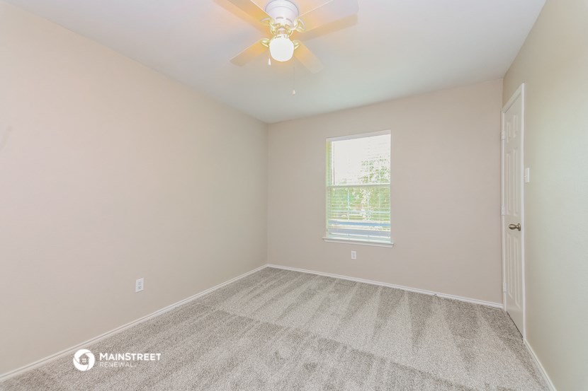 an empty bedroom with a ceiling fan and a window