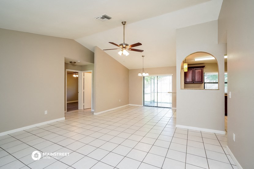 an empty living room with a ceiling fan
