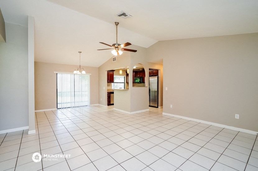 an empty living room with tile flooring and a ceiling fan