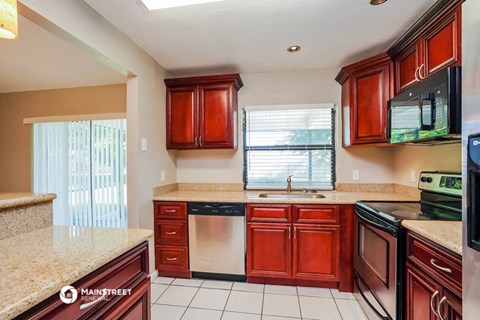 a kitchen with wooden cabinets and granite counter tops and a sink