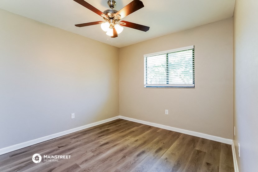the spacious living room with hardwood floors and a ceiling fan