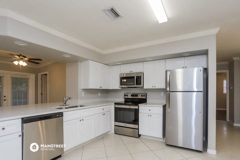 a white kitchen with stainless steel appliances and white cabinets