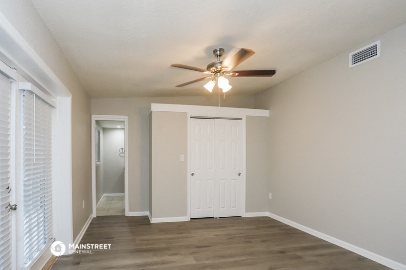 an empty living room with a ceiling fan and a closet