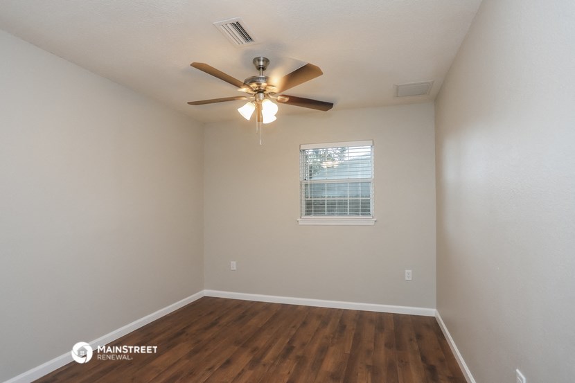 the spacious living room with ceiling fan and wood flooring