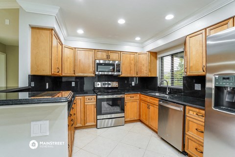 a kitchen with wooden cabinets and black counter tops and stainless steel appliances