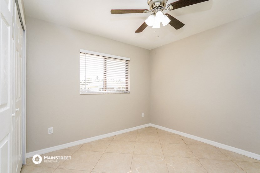 an empty room with a ceiling fan and a window