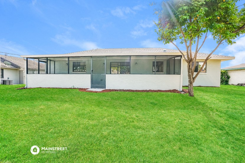 a white house with a lawn and a tree