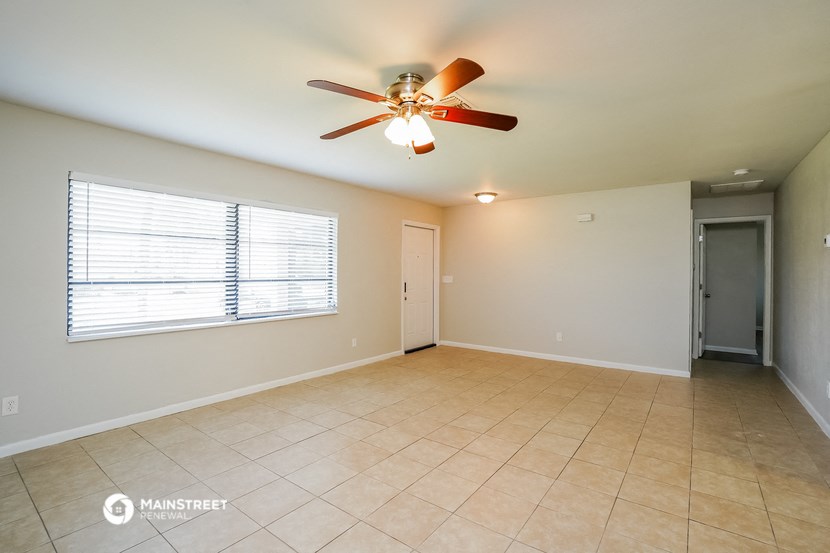 an empty living room with a ceiling fan and a window